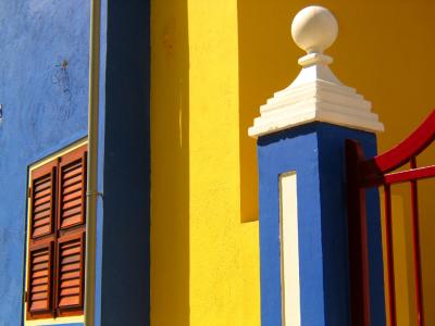 "All of the primary colors – red, yellow, and blue – are present on this boldly painted gate before a beautifully restored house on one of the Caribbean’s most prosperous islands. The light is as bold as the color – the interplay of light and shadow enriches the color with a three dimensional effect. The perfect condition of these sleek colors tell us that whoever lives here appreciates beauty and has the means to maintain it. All of which provides a good metaphor for Willemstad itself." Source: www.pbase.com.